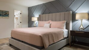 A modern bedroom with a large bed, two bedside lamps, and a geometric-patterned wall. - Cozy house w/ putting green, mtn. views, BBQ (Fountain Hills)