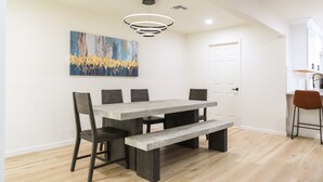 A dining area with a wooden table, benches, and chairs. There is a painting on the wall and a ceiling light fixture. - Cozy house w/ putting green, mtn. views, BBQ (Fountain Hills)