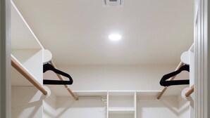 A walk-in closet with wooden flooring, white walls, and a central shelving unit. - Cozy house w/ putting green, mtn. views, BBQ (Fountain Hills)