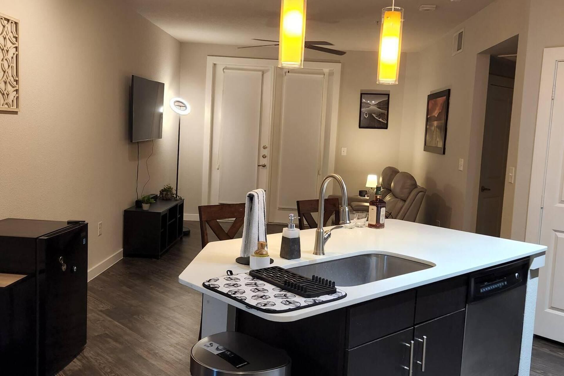A modern kitchen with a white countertop, black cabinets, a built-in dishwasher, and a black stove.