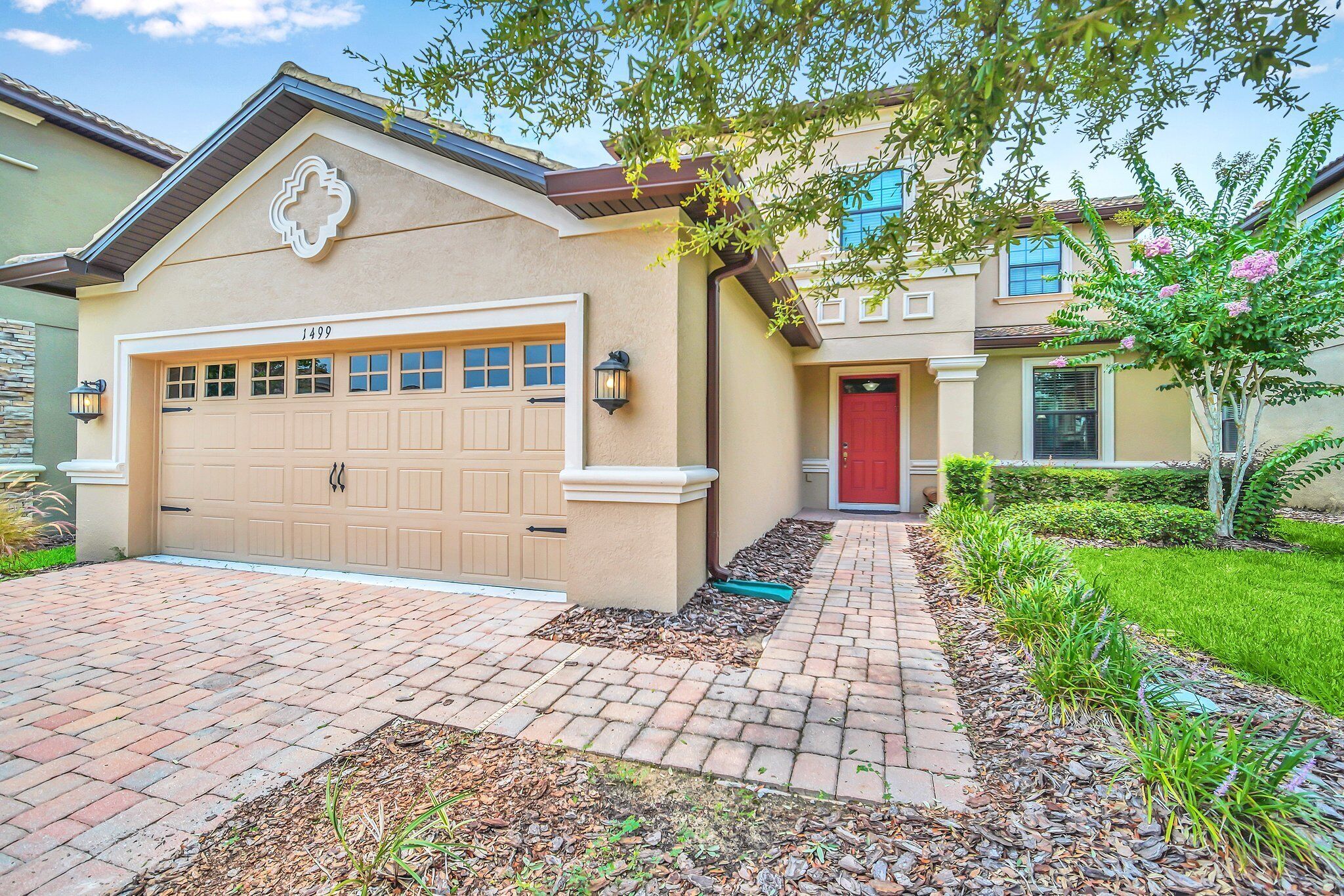 A residential house with a beige facade, a red door, and a garage numbered 1499.