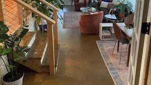 A spacious living area with a staircase, a sofa set, and a dining area. - 2BR/2BA, Clean, Comfy & Steps from Dining & Sound w/ Tesla charging station  (Emerald Isle)