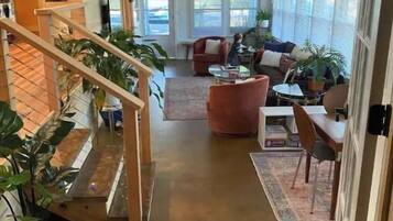 A spacious living area with a staircase, a sofa set, and a dining area.