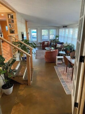 Stunning interior space with a high ceiling, polished floor, and a wooden staircase leading to a cozy seating area.