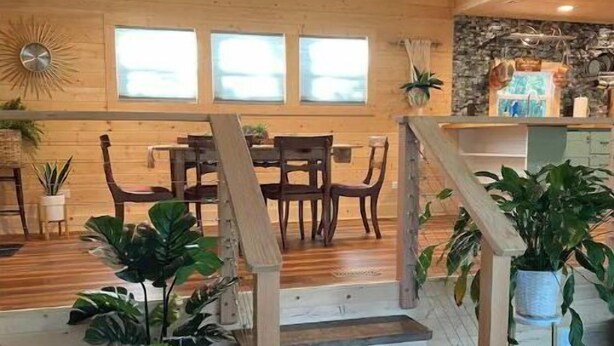 A wooden staircase leading to a dining area with a stone accent wall, potted plants, and a view of the outdoors. - 2BR/2BA, Clean, Comfy & Steps from Dining & Sound w/ Tesla charging station  (Emerald Isle)