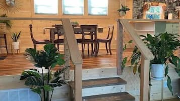 A wooden staircase leading to a dining area with a stone accent wall, potted plants, and a view of the outdoors.