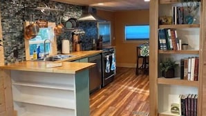 A modern kitchen with wooden flooring, a central island, and a stone backsplash. - 2BR/2BA, Clean, Comfy & Steps from Dining & Sound w/ Tesla charging station  (Emerald Isle)