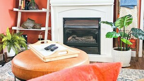 A living room with a fireplace, a television mounted above it, and a wooden ladder leaning against the wall.