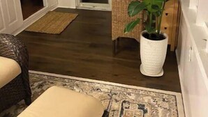 A cozy room with a dining table, a potted plant, and a wicker chair.
