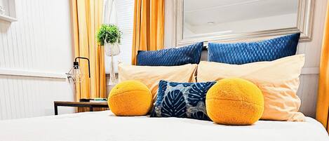 A hotel room with a bed, a blue blanket, and two chocolate packages on the bed.