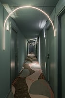A hallway with a patterned carpet, doors on both sides, and a curved light fixture above.