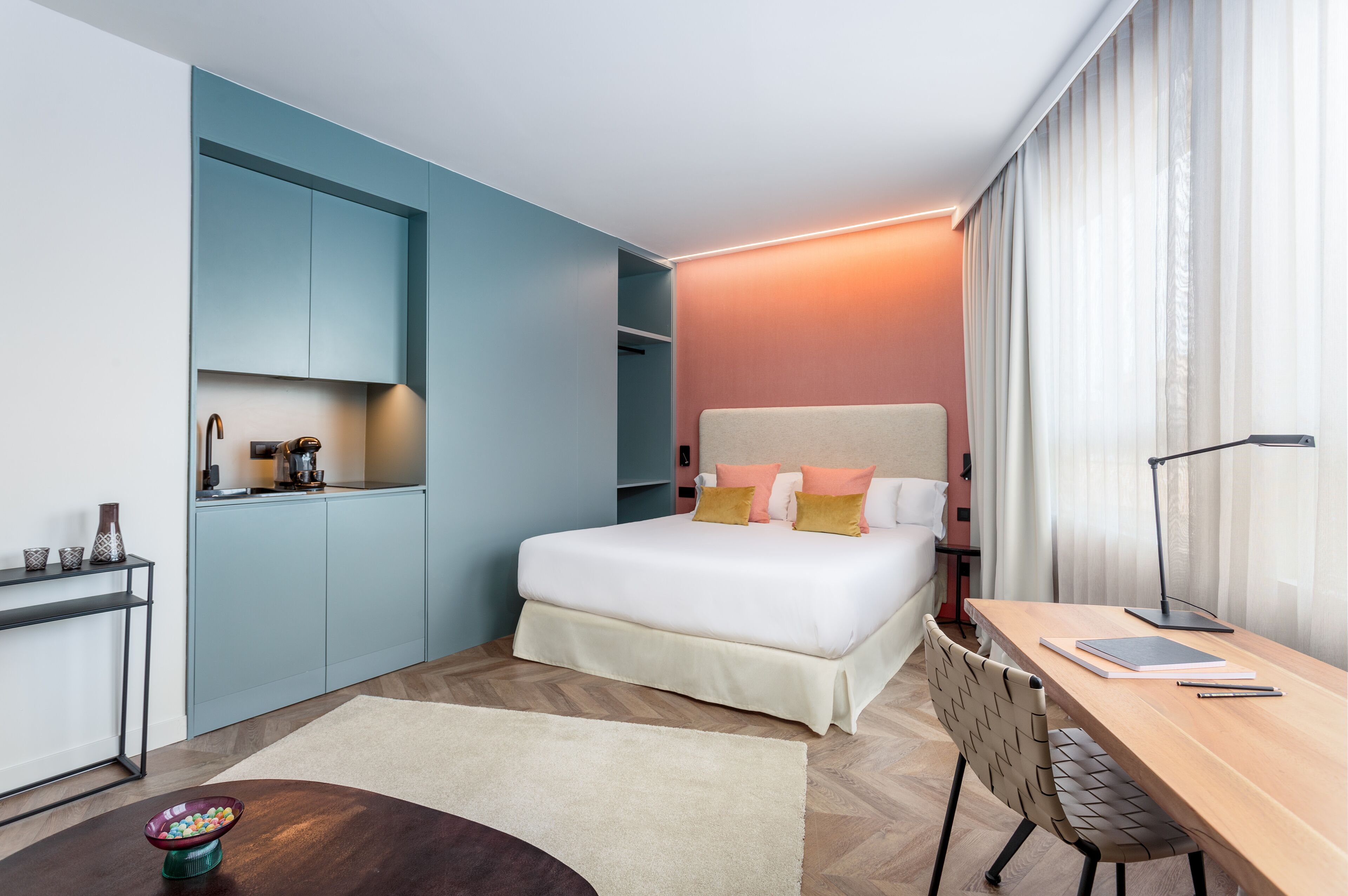 Una habitación de hotel moderna con cama, escritorio y kitchenette.