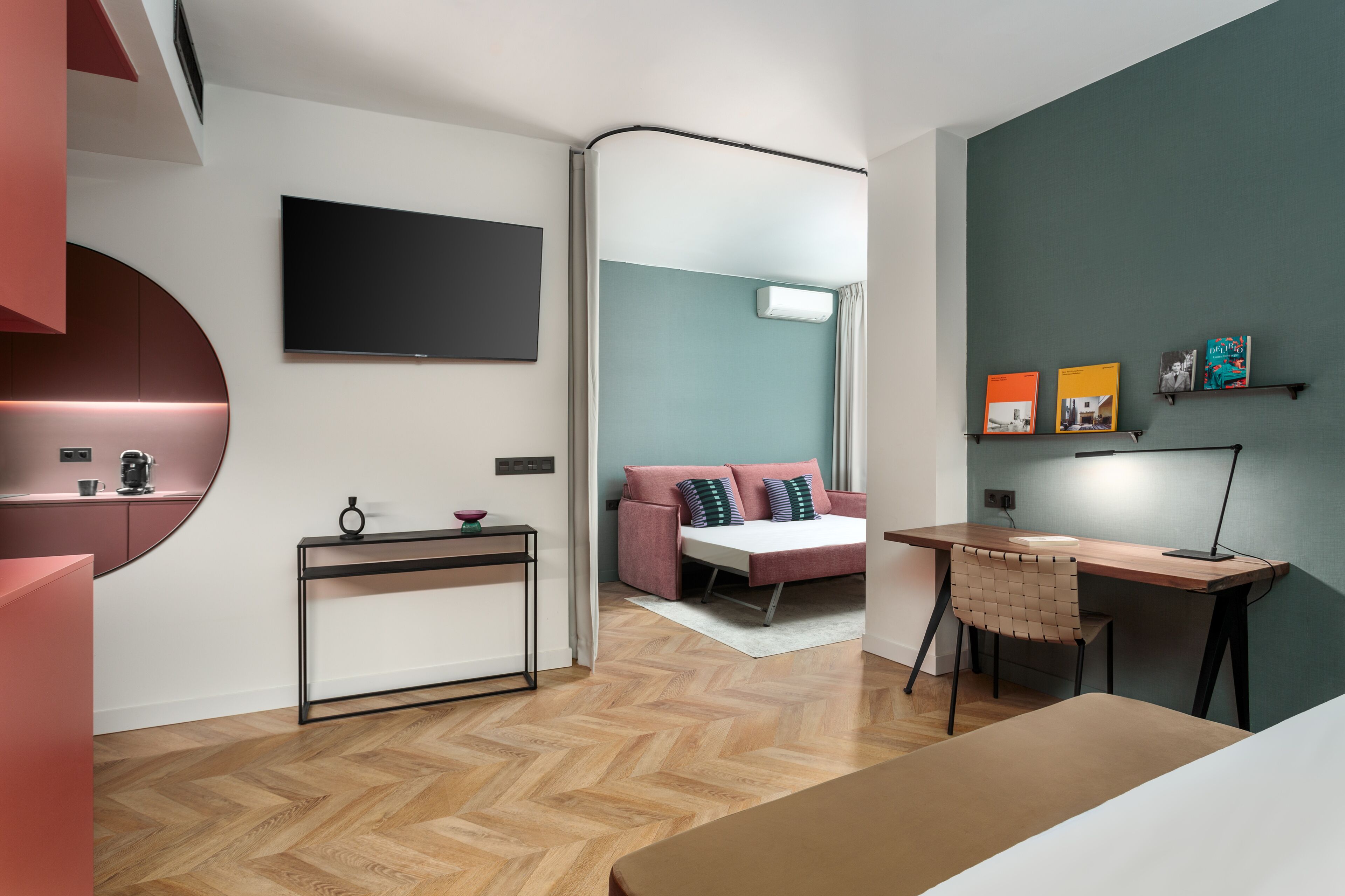 A modern bedroom with a bed, a desk, a TV, and a bookshelf.
