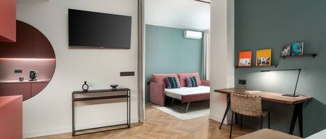 A modern bedroom with a bed, a desk, a TV, and a bookshelf.