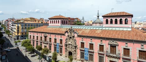 A historic building with a pink facade, ornate architectural details, and a tiled roof.