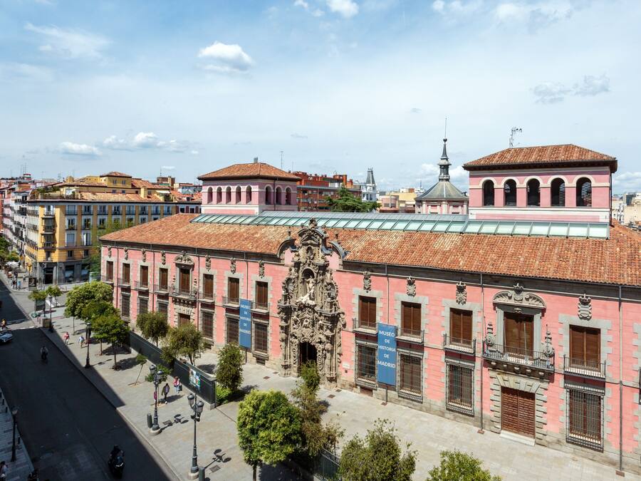 Un bâtiment historique à la façade rose, doté de détails architecturaux raffinés et d’un toit recouvert de tuiles.