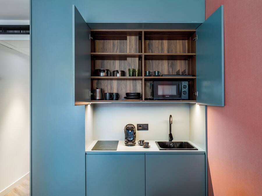 A compact kitchenette with a microwave, coffee maker, and sink.
