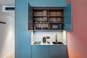 A compact kitchenette with a microwave, coffee maker, and sink.