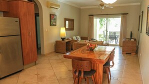 Una cocina con una mesa y sillas de madera, un refrigerador, mobiliario de mimbre y vistas al exterior.