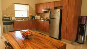 Cocina moderna con armarios de madera, electrodomésticos de acero inoxidable y una mesa de comedor de madera con un florero.