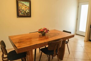 A dining area with a wooden table and four chairs, a vase of flowers, and a painting on the wall. - Elegant 2-bedroom apartment in Ocean Dream (Cabarete)