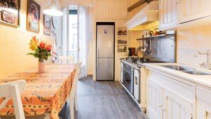 Cozinha com mesa de jantar, cadeiras, geladeira, forno e pia.