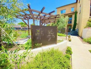 Relax in a serene outdoor space surrounded by lush greenery and a clear sky, under a charming pergola.