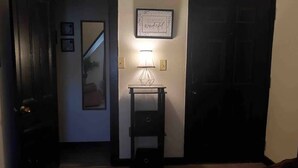 Un couloir avec une lampe, une citation encadrée accrochée au mur et un miroir.
