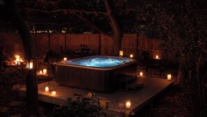 Ein Whirlpool, umgeben von Kerzen und Bäumen in einem Garten.