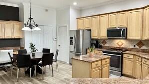 Een moderne keuken met houten kastjes, roestvrijstalen apparatuur en een granieten aanrecht.