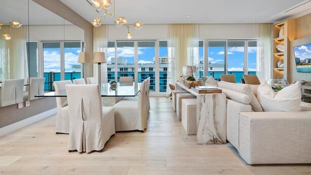 A spacious living room with a large window overlooking the sea, a modern chandelier, and a comfortable seating area. - Premium 3-Bedroom Oceanview Penthouse at 1 Hotel (Miami Beach)
