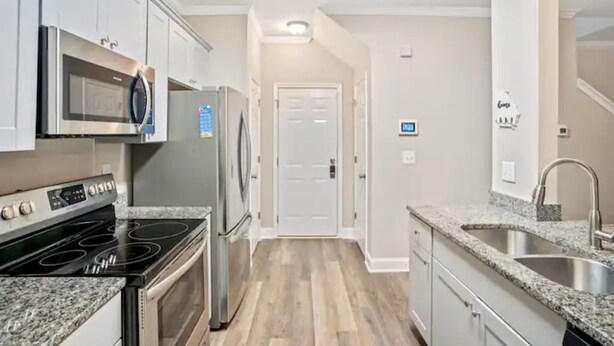 Una cocina moderna con electrodomésticos de acero inoxidable, encimeras de granito y suelo de madera.