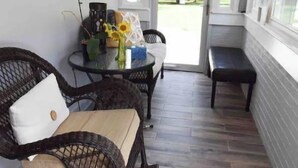Una habitación soleada con muebles de mimbre, una mesa de vidrio y un banco.