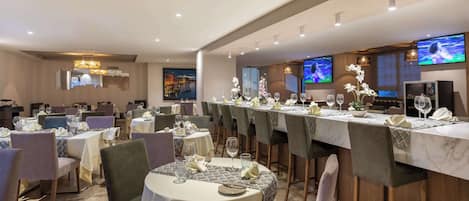 A restaurant with multiple tables set for dining, equipped with wine glasses and cutlery.