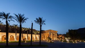 A grand hotel with a courtyard, palm trees, and illuminated arches. - Royal Tulip Korbous Bay Thalasso & Springs (Qurbus)