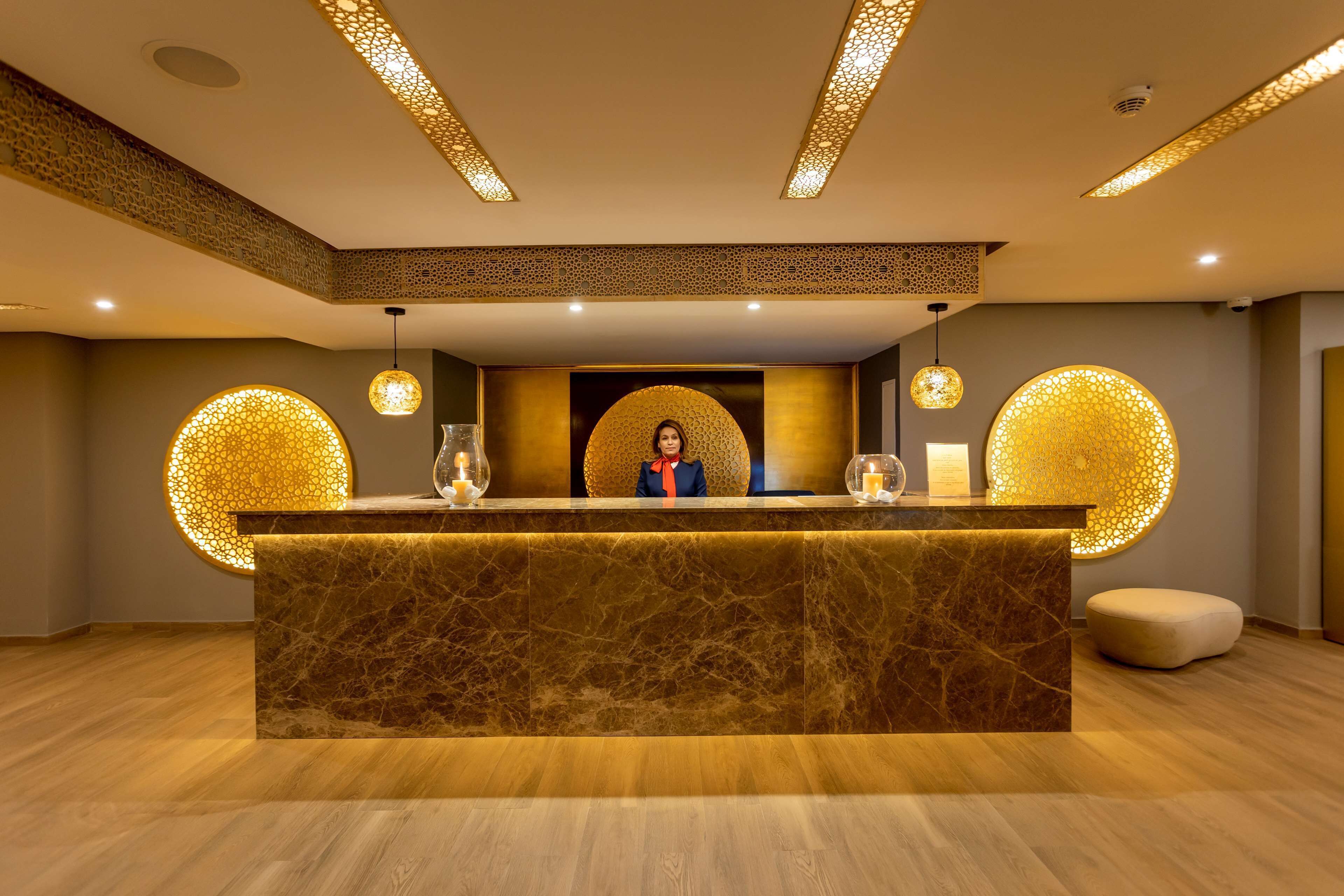 A reception area with a marble counter, decorative lighting, and a receptionist.