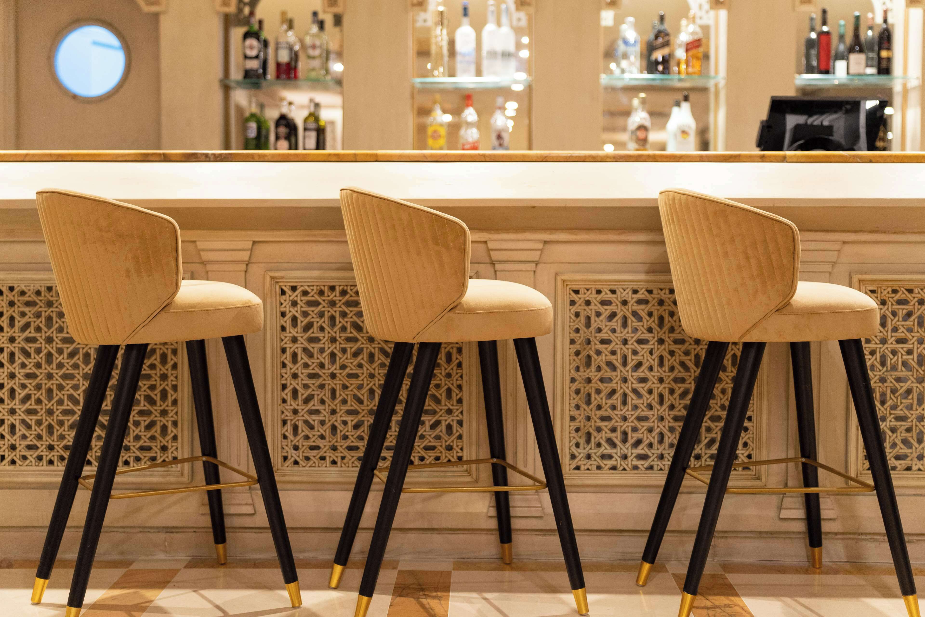 A bar area with three bar stools and a bar counter.