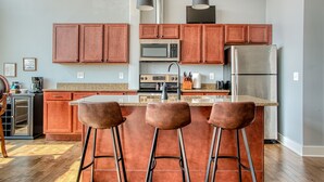 Eine moderne Küche mit Holzausstattung, Edelstahlgeräten und einer zentralen Kochinsel mit Barhocker.
