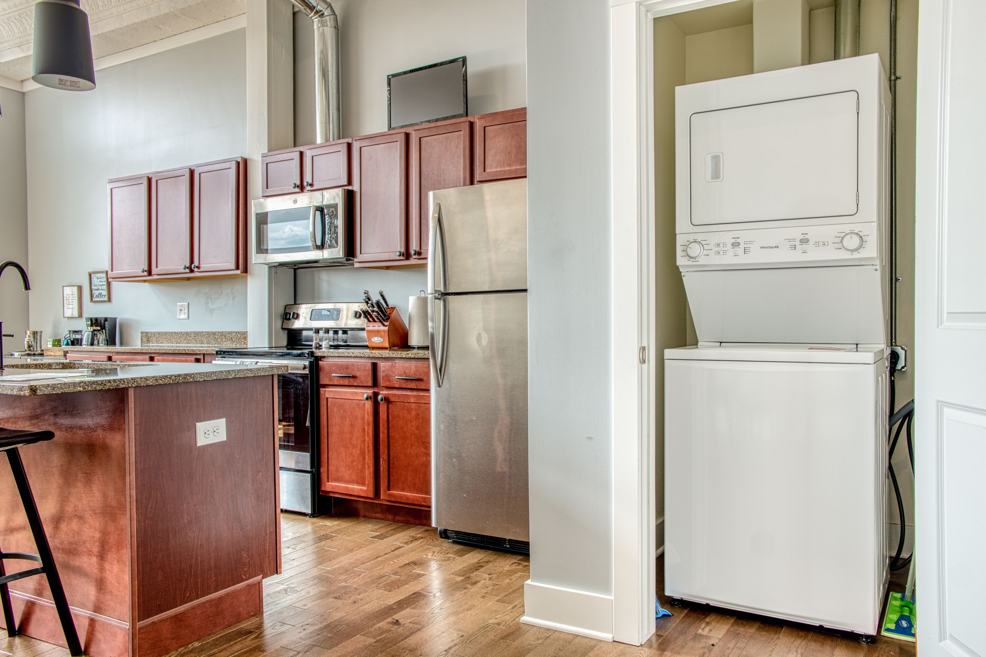 A kitchen with wooden cabinets, a stainless steel refrigerator, a microwave, and a dishwasher.