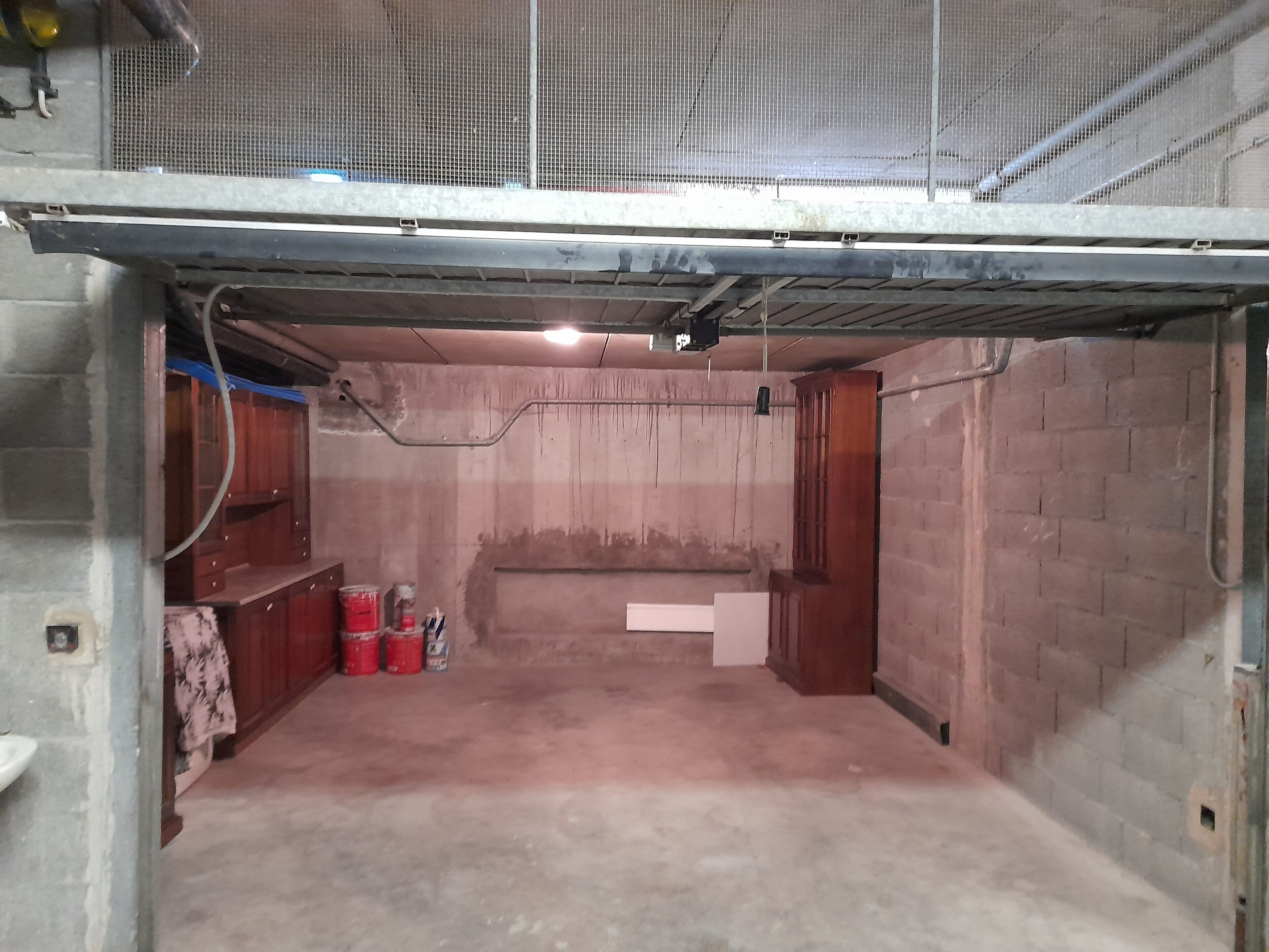 Un sous-sol avec des murs en béton, une porte en métal et une armoire en bois.