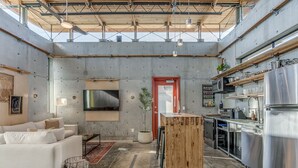 A modern interior with a living area, kitchen, and a large window. - NEW INDUSTRIAL STUDIO - walking distance to UCO! (Edmond)