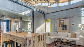 A modern interior with a wooden bar area, a white sofa, and a large mirror. - NEW INDUSTRIAL STUDIO - walking distance to UCO! (Edmond)