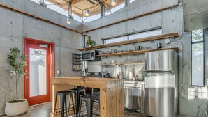 A modern kitchen with a central island, stainless steel appliances, and a red door. - NEW INDUSTRIAL STUDIO - walking distance to UCO! (Edmond)