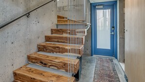 A modern interior with a concrete wall, a blue door, and a wooden staircase with metal railings. - NEW INDUSTRIAL STUDIO - walking distance to UCO! (Edmond)