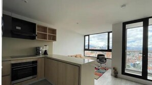 Una cucina moderna con forno integrato, macchina del caffè e vista sulla città attraverso ampie finestre.