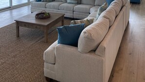 Una sala de estar amplia con un sofá modular grande, una mesa de centro y un ventilador de techo.