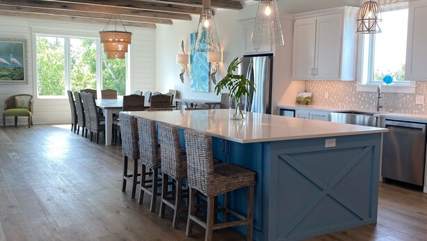 Una cocina amplia con una isla grande, suelo de madera e iluminación colgante.