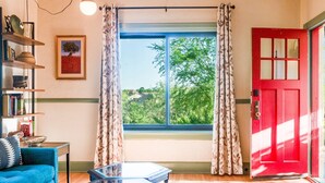 A living room with a blue sofa, a glass coffee table, and a red door. - Sunny Historic Cottage, Wineries, Outdoor Living, Verde Train, Jerome (Clarkdale)
