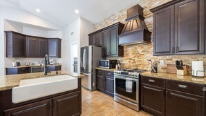 Una cucina moderna con mobili in legno scuro, piani in granito, elettrodomestici in acciaio inossidabile e una parete rivestita in pietra.