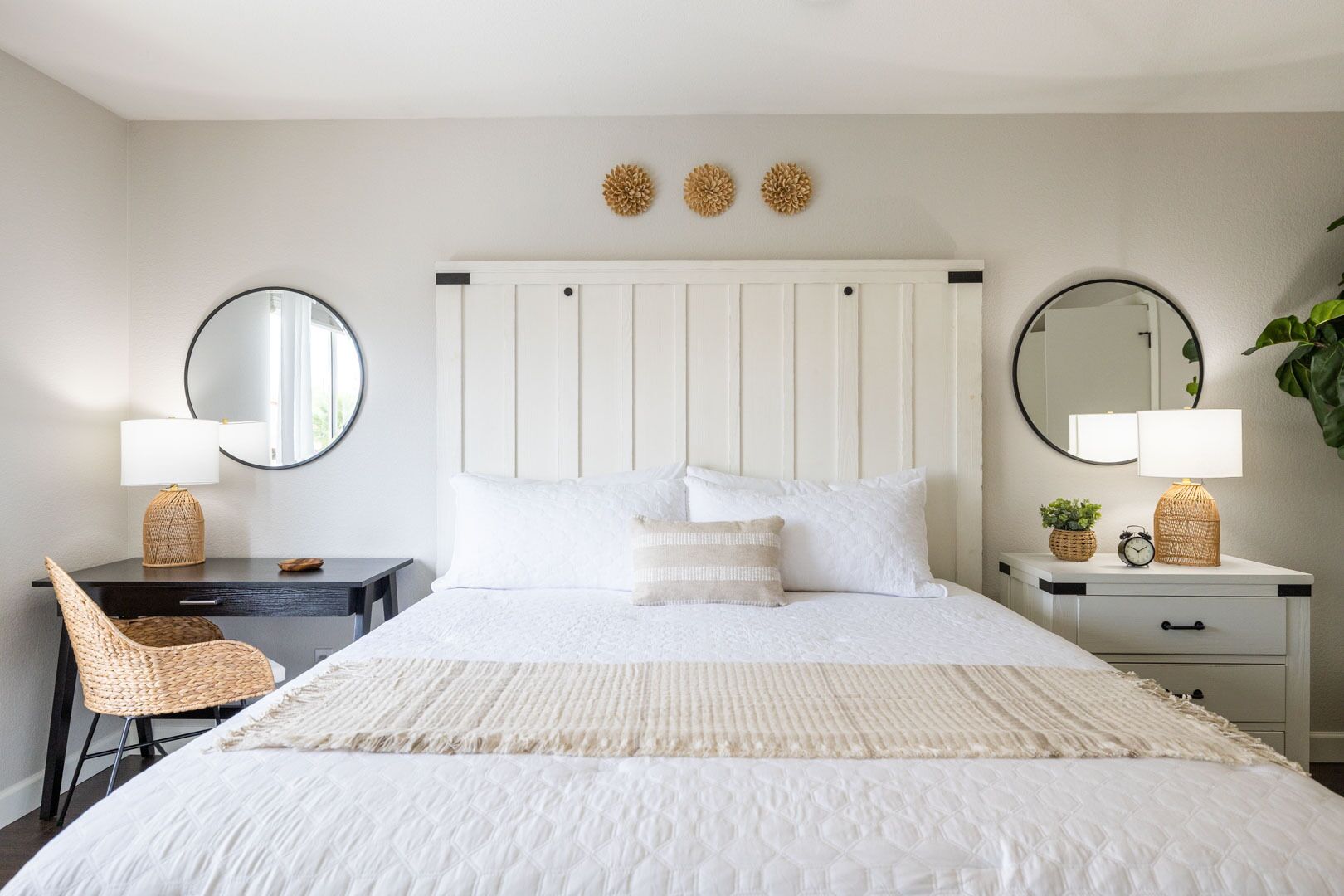 Una camera da letto con un letto, due comodini, una sedia e elementi decorativi alle pareti.
